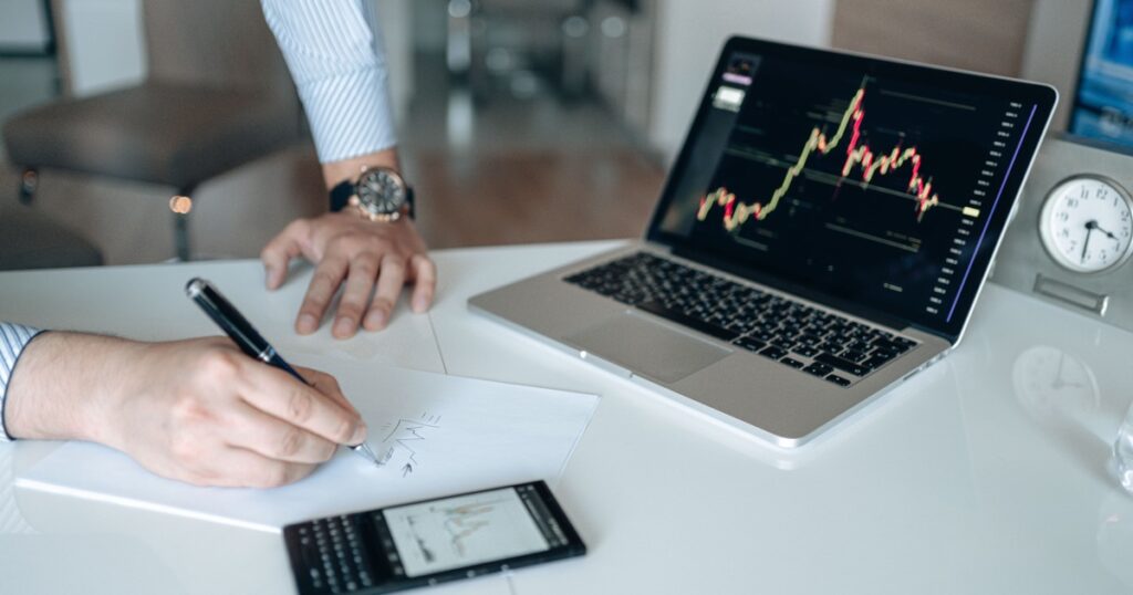 ノートにメモを取りながら金融チャートを分析している様子