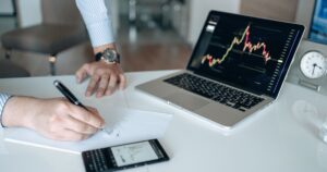 ノートにメモを取りながら金融チャートを分析している様子